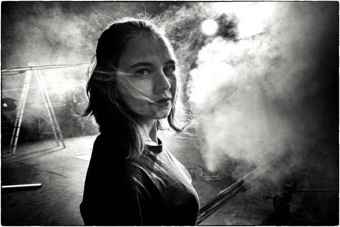 Portraitfoto einer jungen Frau mit zerzaustem Haar in dramatischer Kulisse mit Nebel